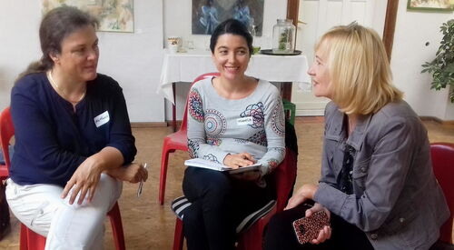 3 Frauen sitzen beieinander, blicken sich an. Im Gespräch.